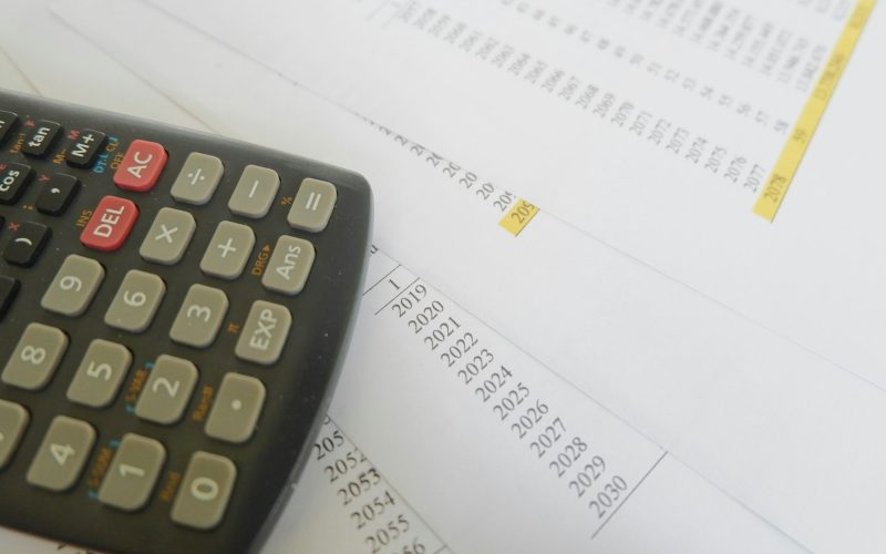 High angle shot of a calculator on documents of debts – concept of loans and banking High angle shot of a calculator on documents of debts - concept of loans and banking